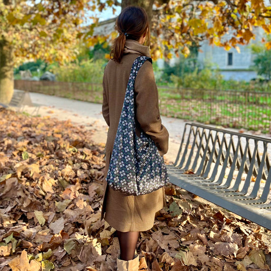 <img src=sac-hobo-porte-a-l-epaule-par-modele-debout-de-trois-quart-dos-devant-un-banc-en-automne.jpeg" alt="